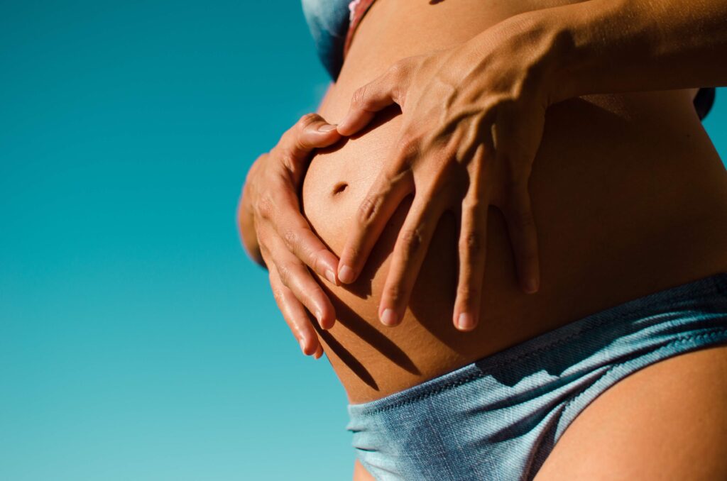 一位皮膚黝黑的孕婦在肚皮上比心